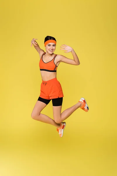 Excitée sportive souriant à la caméra tout en sautant isolé sur jaune — Photo de stock