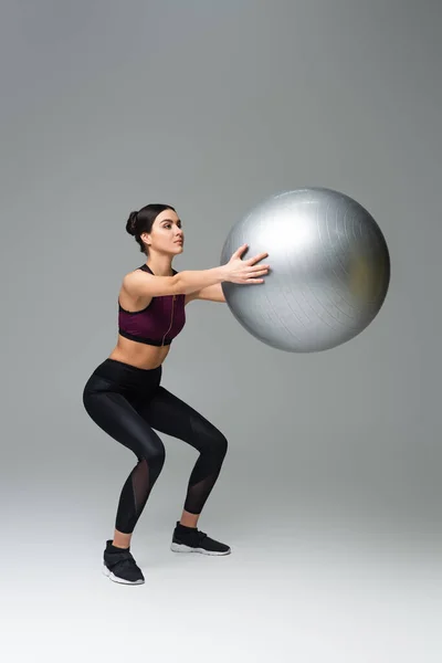 Sportlerin macht Sit-Ups mit Fitnessball auf grauem Hintergrund — Stockfoto