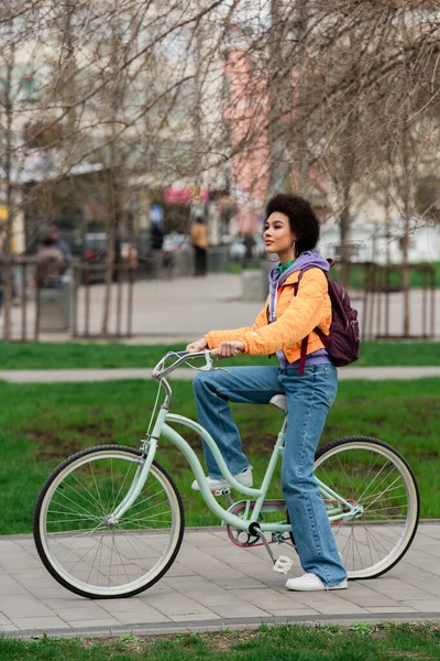 African american woman riding bicycle on urban street — Stock Photo