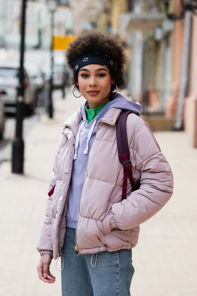 Femme afro-américaine en veste regardant la caméra sur la rue urbaine — Photo de stock