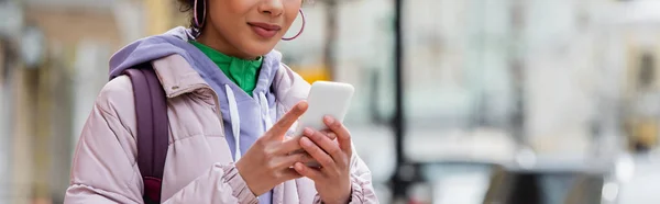 Vista cortada da mulher americana africana elegante com smartphone na rua urbana, banner — Stock Photo