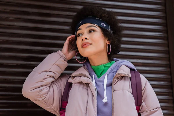 Elegante donna afro-americana in piedi vicino a otturatore sfocato — Foto stock