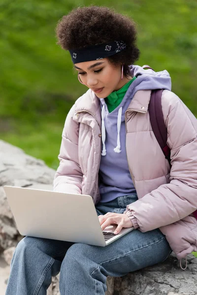 Telelavoro afroamericano che utilizza laptop su parapetto nel parco — Foto stock