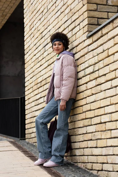 Africano americano mulher olhando para câmera perto de edifício na rua — Fotografia de Stock