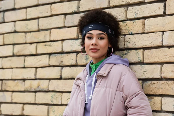 Femme afro-américaine regardant la caméra près de la façade du bâtiment à l'extérieur — Photo de stock