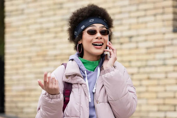 Happy african american woman in sunglasses talking on smartphone outdoors — Stock Photo