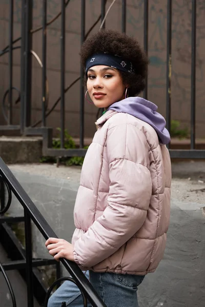 Afroamerikanerin mit Kopftuch und Jacke blickt im Freien in die Kamera — Stockfoto