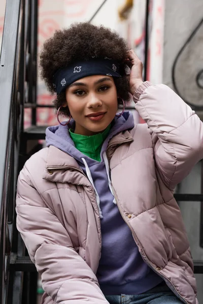 Jolie femme afro-américaine en bandana regardant la caméra dans les escaliers — Photo de stock