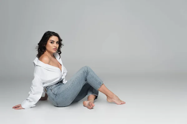 Mujer seductora en camisa blanca posando sobre fondo gris - foto de stock