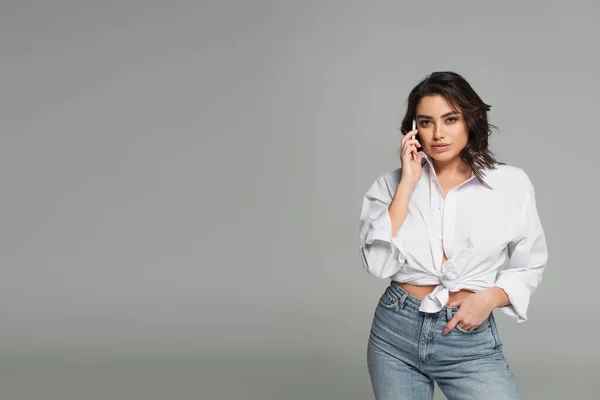 Gorgeous woman talking on mobile phone isolated on grey — Stock Photo