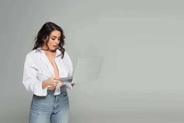 Mulher sexy segurando laptop isolado no cinza — Fotografia de Stock