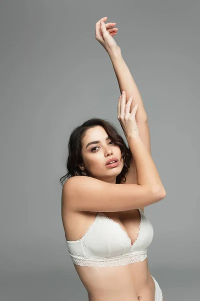 Jolie femme en soutien-gorge touchant les mains isolées sur gris — Photo de stock