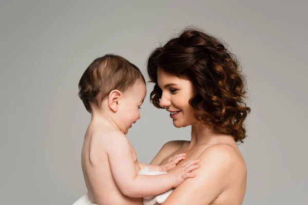 Side view of happy mother holding son in arms isolated on grey — Stock Photo