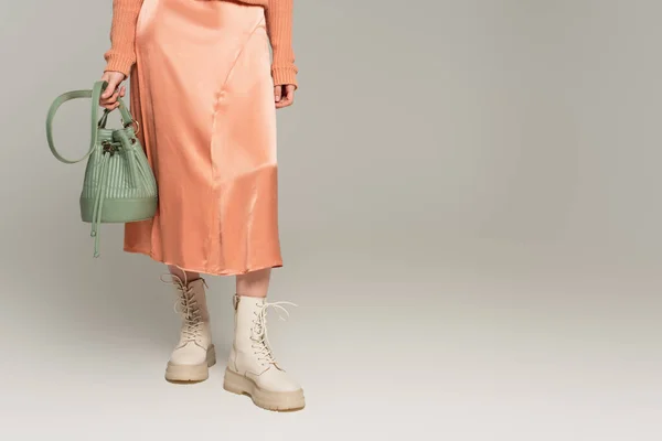 Partial view of stylish woman in silk skirt holding bag on grey — Stock Photo