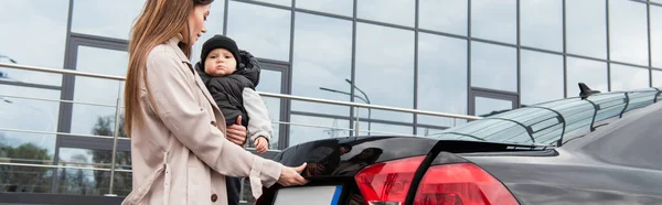 Jovem mãe segurando criança perto de automóvel, banner — Fotografia de Stock