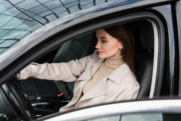 Pretty young woman sitting in car at steering wheel — Stock Photo