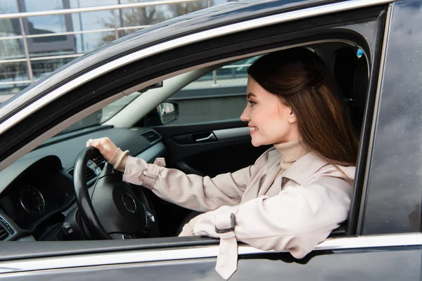 Bella giovane donna sorridente durante la guida auto in città — Foto stock