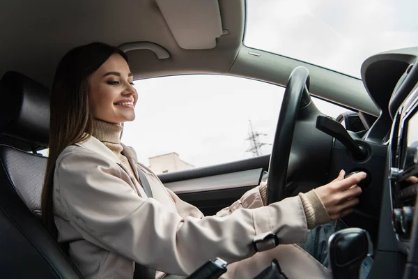 Весела жінка посміхається під час запуску двигуна автомобіля — стокове фото