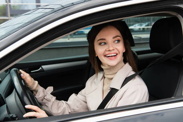 Веселая молодая женщина смотрит в сторону за рулем автомобиля — стоковое фото