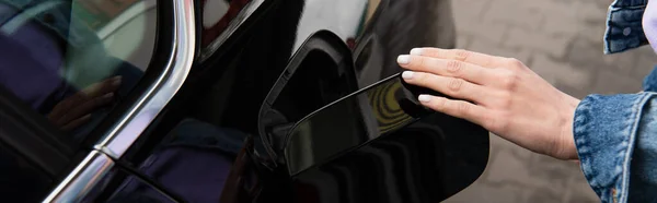 Vue partielle de la femme ouvrant le réservoir de carburant de la voiture noire, bannière — Photo de stock