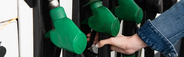 Partial view of female hand near fuel pistols on gas station, banner — Stock Photo