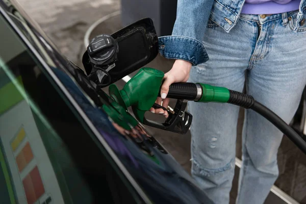Frau in Jeans tankt Auto an Tankstelle — Stockfoto