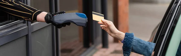 Partial view of driver with credit card near cashier with payment terminal, banner — Stock Photo