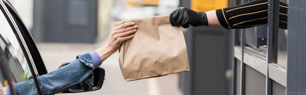 Teilansicht des Fahrers, der dem Verkäufer in Latexhandschuhen Lebensmittel zum Mitnehmen wegnimmt, Banner — Stockfoto