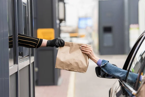 Cropped view of cashier giving takeaway food to driver in car — Stock Photo
