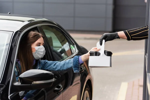 Motorista em máscara médica tomar café para ir de caixa — Fotografia de Stock