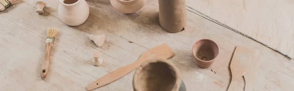 Visão de alto ângulo de vasos de barro artesanais com espátulas na mesa de madeira em cerâmica, banner — Fotografia de Stock