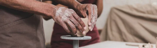 Vue partielle du jeune homme afro-américain sculptant pot d'argile en poterie, bannière — Photo de stock