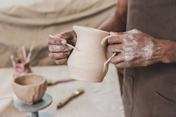 Vista parziale del giovane uomo afro-americano scolpire vaso di argilla con bastone in ceramica — Foto stock