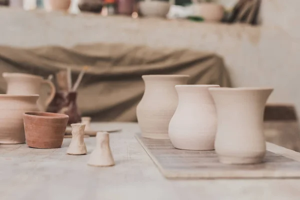 Ollas de arcilla hechas a mano en la mesa de madera en el estudio de cerámica - foto de stock