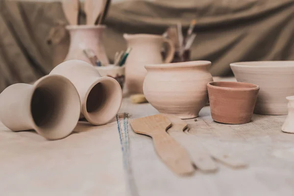 Ollas de arcilla hechas a mano y equipos de cerámica en la mesa de madera en el estudio de arte - foto de stock