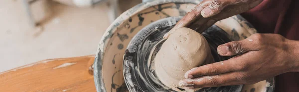 Close up view of young african american man modeling wet clay on wheel in pottery, banner — Stock Photo