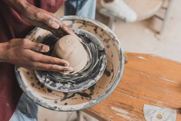 Close up view of young african american man modeling wet clay on wheel in pottery — Stock Photo