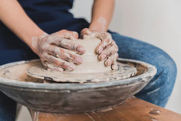 Partial view of young african american woman modeling wet clay on wheel with hands in pottery — Stock Photo