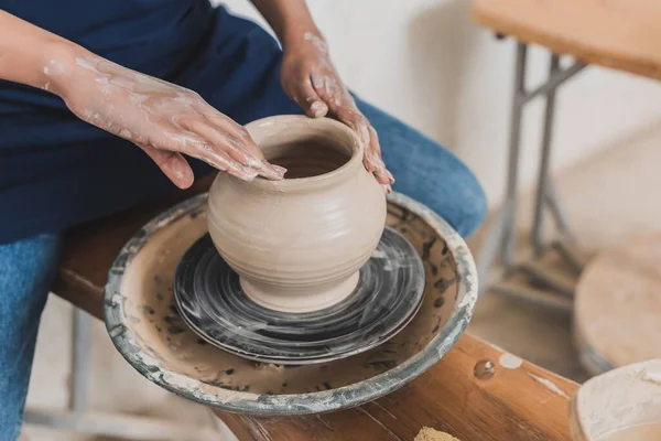 Vue partielle de jeune femme afro-américaine modelant pot d'argile humide sur roue avec les mains en poterie — Photo de stock