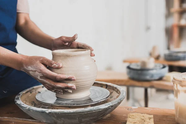 Partial view of young african american woman modeling wet clay pot on wheel in pottery — Stock Photo