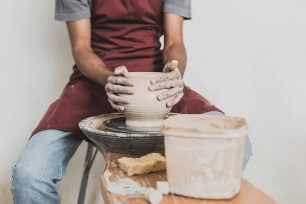 Partial view of young african american man modeling wet clay pot on wheel in pottery — Stock Photo