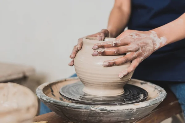 Partial view of young african american woman modeling wet clay pot on wheel in pottery — Stock Photo