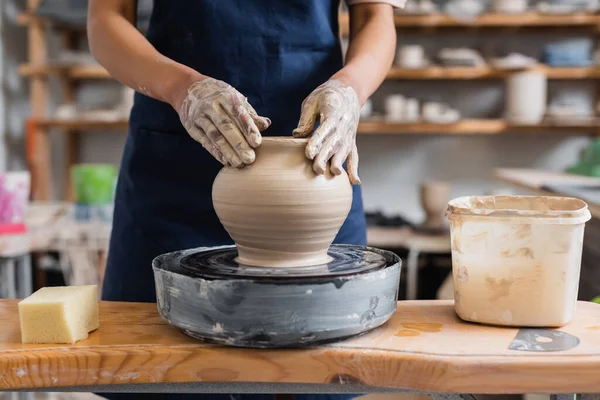 Vista parziale di giovane donna afro-americana modellare pentola di argilla bagnata su ruota in ceramica — Foto stock