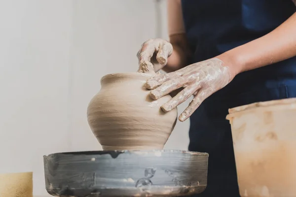 Partial view of young african american woman shaping wet clay pot on wheel with hands in pottery — Stock Photo