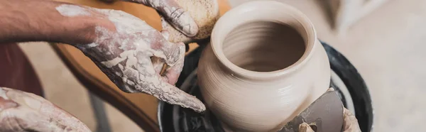 Vue rapprochée du jeune couple afro-américain façonnant un pot d'argile humide sur roue avec les mains et grattoir en poterie, bannière — Photo de stock
