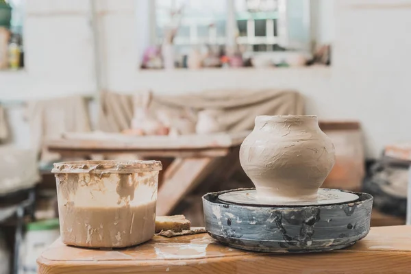 Pote de barro molhado esculpido na roda de cerâmica na mesa de madeira no estúdio de arte — Fotografia de Stock