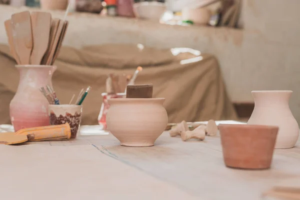 Handmade clay pots with pottery equipment on wooden table — Stock Photo