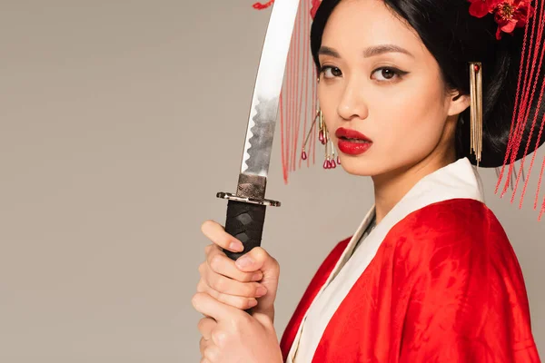 Asiatin im Kimono hält Schwert isoliert auf grau — Stockfoto
