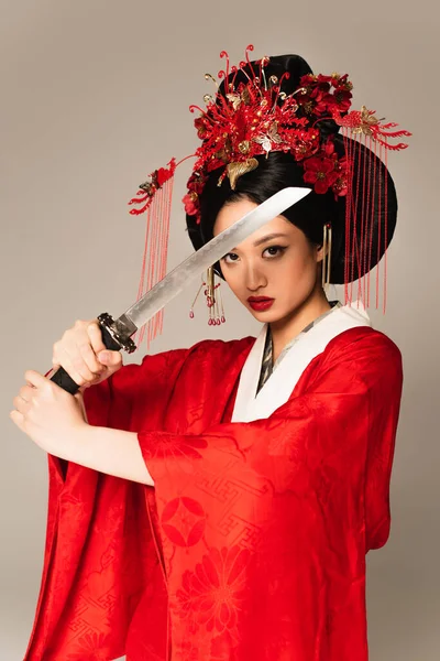 Japanese woman in kimono holding sword isolated on grey — Stock Photo