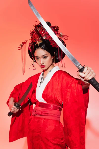 Mujer japonesa sosteniendo espadas sobre fondo rojo - foto de stock